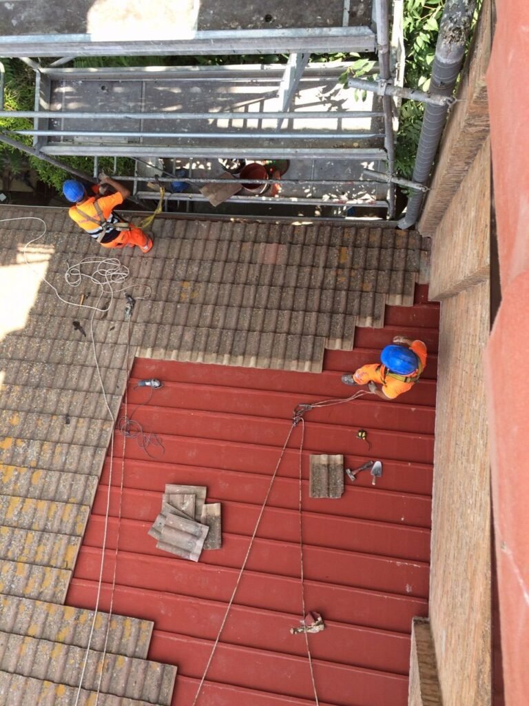 Operarios con arnés impermeabilizando una cubierta de teja