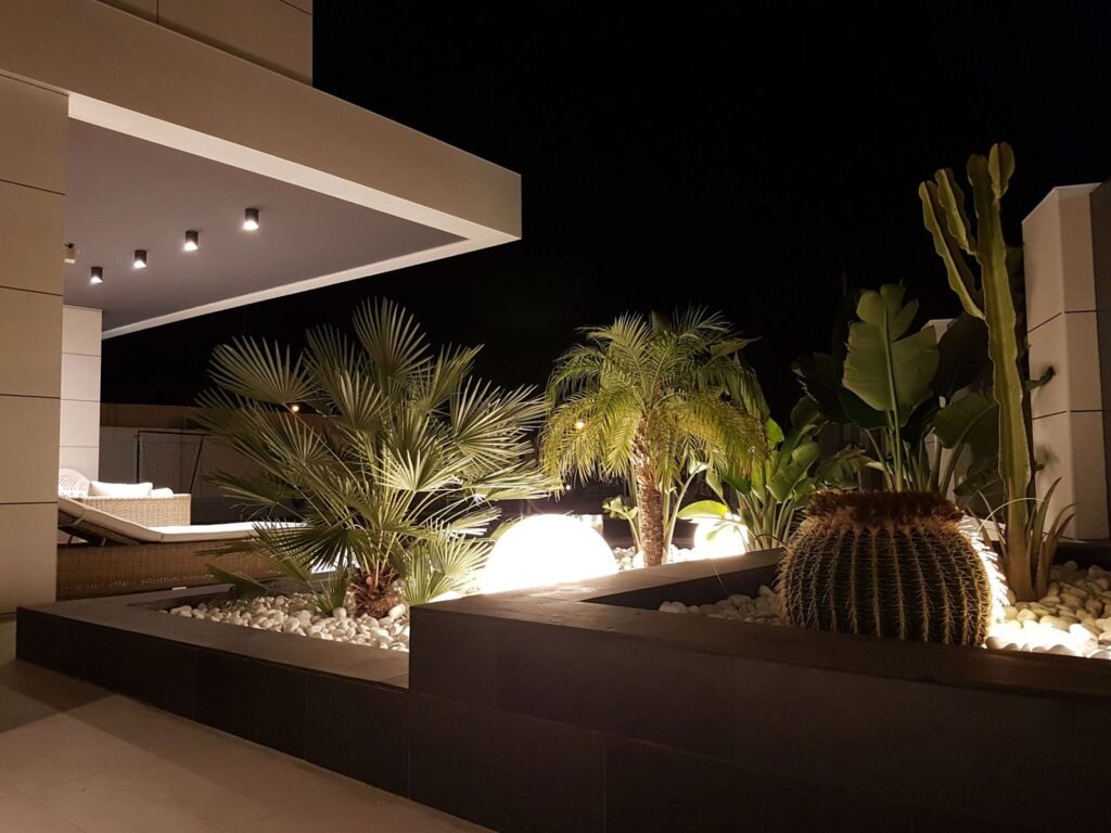 Jardín iluminado de noche junto al porche de una vivienda unifamiliar